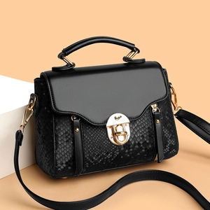 Chic black snake print crossbody bag with gold buckle on minimalist props