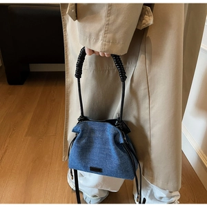 Detailed close-up of blue denim dumpling bag with unique black spiral spring handle