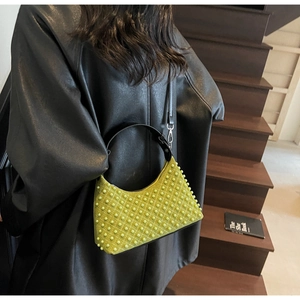 Close-up of bright green studded shoulder bag with crescent silhouette and black handle