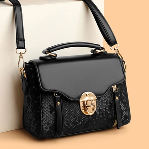 Classic black crossbody bag with snakeskin texture and gold hardware on elegant display