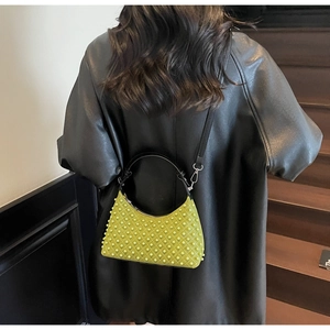 Detail of neon green shoulder bag with pearl studs worn over a black leather jacket