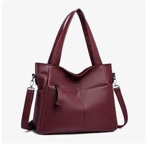 Macro detail of wine red tote bag showing lychee grain leather texture and metallic zippers