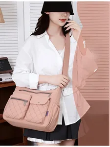 Pink nylon crossbody bag with quilted pockets and wide strap worn by a model