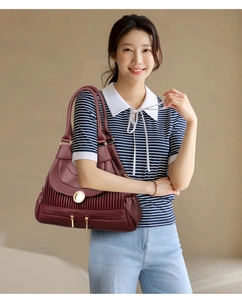 Détails d'un sac à main bordeaux plissé en cuir avec boucle dorée et poches multiples
