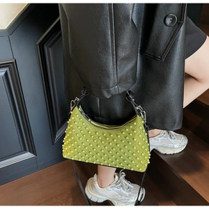 Detail of green hobo bag with pearl texture and sleek black shoulder strap on model