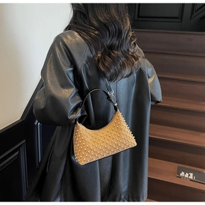 Detailed view of camel suede hobo bag with pearl studs worn with black leather jacket