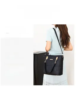 Detail of black faux leather tote bag with crocodile pattern and gold metal chain strap