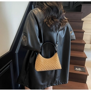 Detailed view of khaki crescent bag with pearl texture and black shoulder strap on model