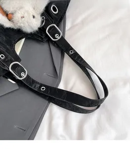 Detail of black tote with wrinkled texture, silver eyelets and plush animal charm
