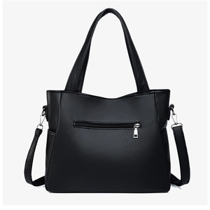 Detail view of large black tote bag featuring lychee texture leather and back zipper pocket