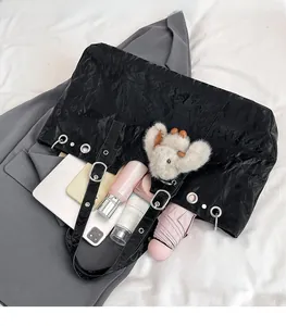 Detail of spacious black tote bag interior showing gadgets and shiny wrinkled texture