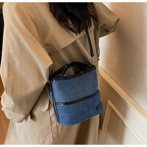 Detail view of denim bucket bag with leather trim and adjustable crossbody shoulder strap