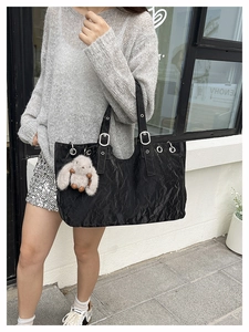 Detail of black wrinkled leather tote bag with silver eyelets and plush rabbit charm