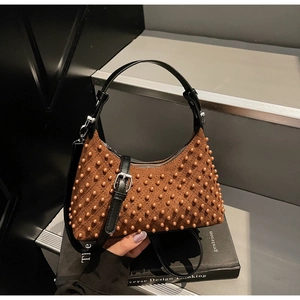 Detail of a crescent brown suede shoulder bag with 3D studs and leather handle