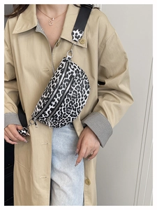 Detail einer Bauchtasche mit Leopardenmuster und silbernen Reißverschlüssen am Model