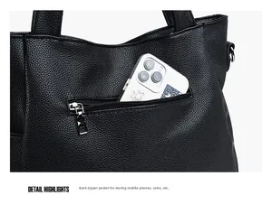 Detail of large black leather tote bag back pocket showing storage for a smartphone