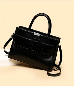 Detail view of glossy oil wax leather handbag with signature square buckle and top handles