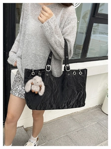 Detail of black tote bag featuring crinkled texture fabric and silver metal eyelets