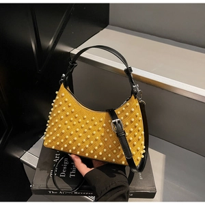 Detailed macro of yellow quilted suede bag with pearl accents on art book stand