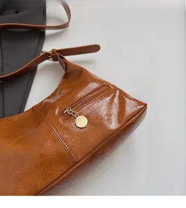 Detail of caramel pleated glossy leather tote with gold pendant and zipper pocket