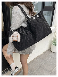 Detail of black textured tote bag with silver metal eyelets and white plush bunny charm