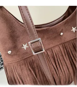 Detail der braunen Wildledertasche mit Sternennieten und verstellbarem Leder-Schultergurt