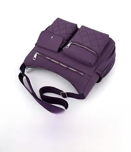 Detail view of purple nylon crossbody bag featuring multiple zipper pockets and flap closure