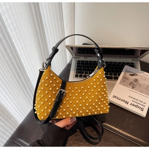 Close-up of yellow suede quilted shoulder bag with pearl rivets and black strap