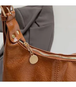 Detailed close-up of brown crinkled leather shoulder bag with gold zipper and rivets