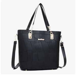Close-up of black crocodile textured pattern and golden hardware on fashionable tote bag