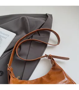 Detail view of brown glossy leather shoulder strap with adjustable gold metal buckle