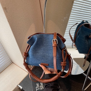 Navy denim cloud bucket bag with brown leather spiral handle and adjustable shoulder strap