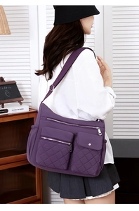 Detail view of purple nylon crossbody bag featuring multi-pocket design and quilted texture
