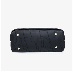 Detail of black patchwork bag bottom with protective gold studs and exotic textures