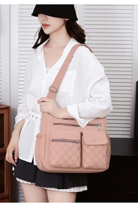 Detail of peach pink nylon crossbody bag with multi-pocket design and adjustable strap
