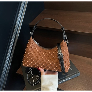 Detail view of brown suede underarm bag with quilted diamond pattern and pearl accents