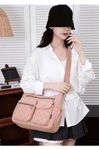 Detail of pink nylon crossbody bag featuring quilted front pockets and wide shoulder strap