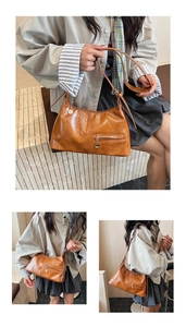 Detail of glossy brown leather tote with metal charm and sleek zipper front pocket