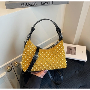 Close-up of yellow suede shoulder bag featuring pearl studs and black leather strap