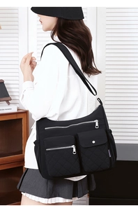 Detail of multi-pocket black nylon crossbody bag with quilted rhombic pattern design