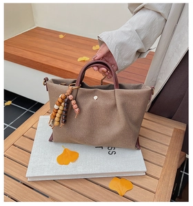 Detail of tan canvas handbag with leather handles and decorative wooden bead tassels