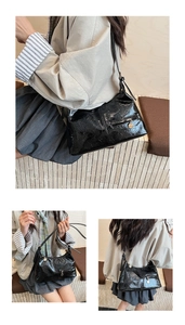 Detail view of black glossy pleated shoulder bag with gold zipper and metal hardware