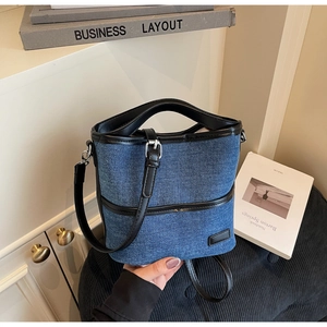 Close-up of blue denim bucket bag featuring black leather trim and detachable shoulder strap