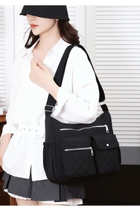 Detailed view of black nylon crossbody bag with multiple pockets and adjustable shoulder strap