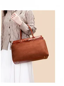 Detail einer braunen Henkeltasche mit Vintage-Lederschnalle und goldenen Beschlägen