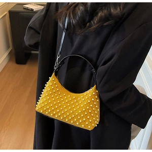 Detail of mustard yellow suede shoulder bag with pearl accents and black leather handle