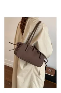 Brown matte Boston shoulder bag shown on a model wearing a beige trench coat