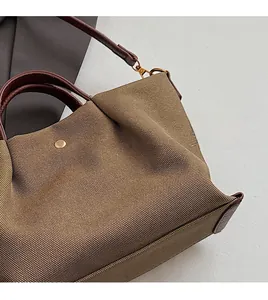 Close-up of canvas texture with brown leather handles and golden metal snap button