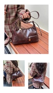Detail of vintage brown oil-wax leather shoulder bag with gold zipper and round pendant