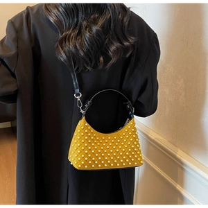 Detail of yellow shoulder bag with white pearl lattice pattern on a black coat model